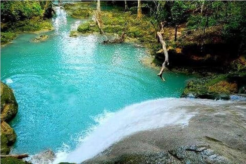 A turquoise river, a waterfall, and a person jumping into the water. 3
