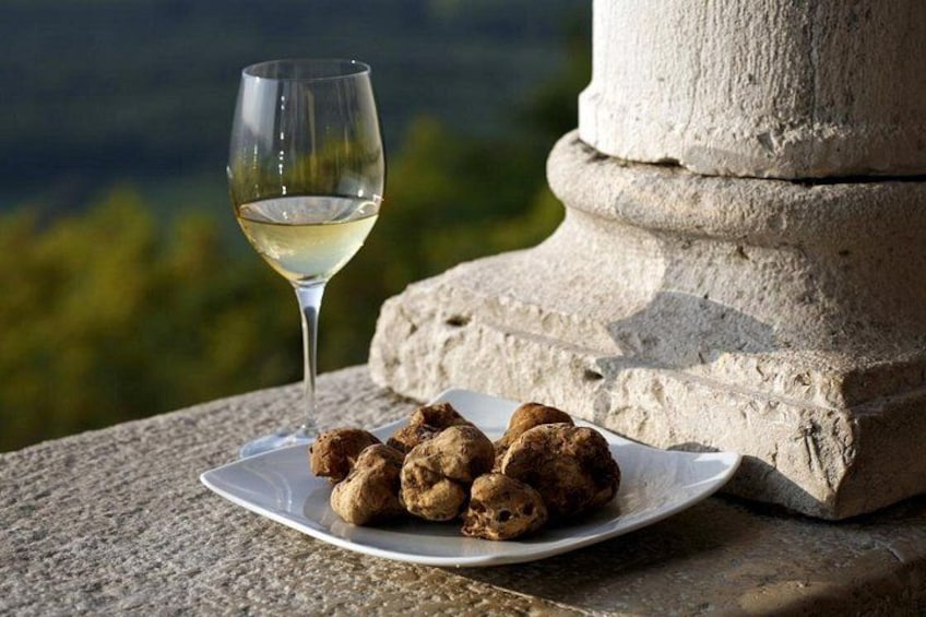 En tallrik mat och ett glas vitt vin står på en stenhylle med ett bergigt landskap i bakgrunden. 1