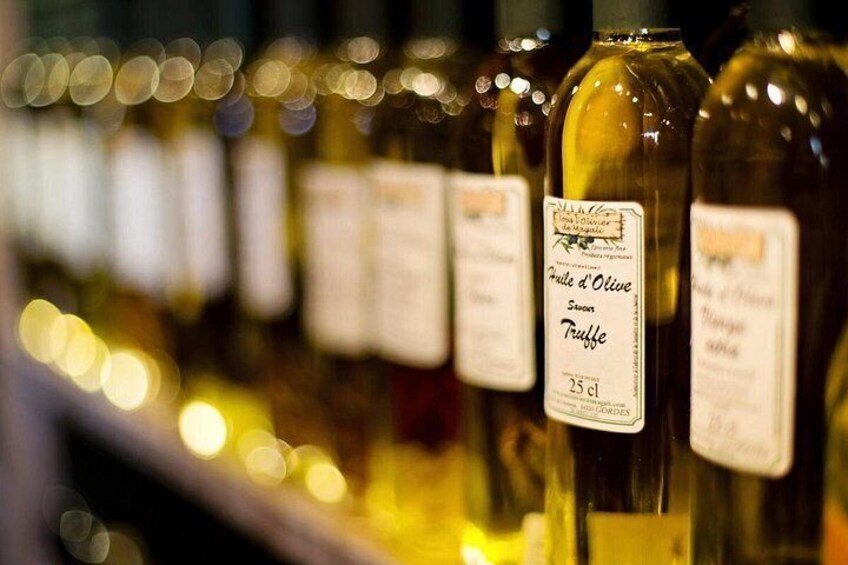 Une rangée de bouteilles, toutes étiquetées et contenant probablement de l’huile d’olive, dans un endroit à la lumière tamisée. 2