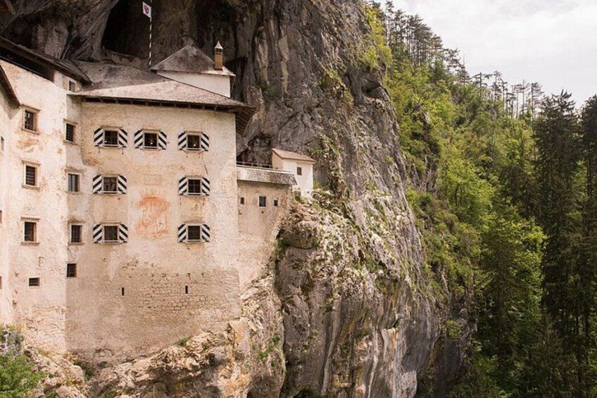 A building nestled in a rocky cliffside with a forested background. 2