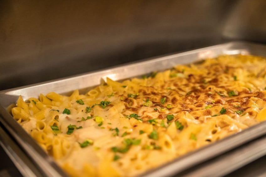 A tray of baked pasta with a golden-brown cheese topping and green herbs. 3