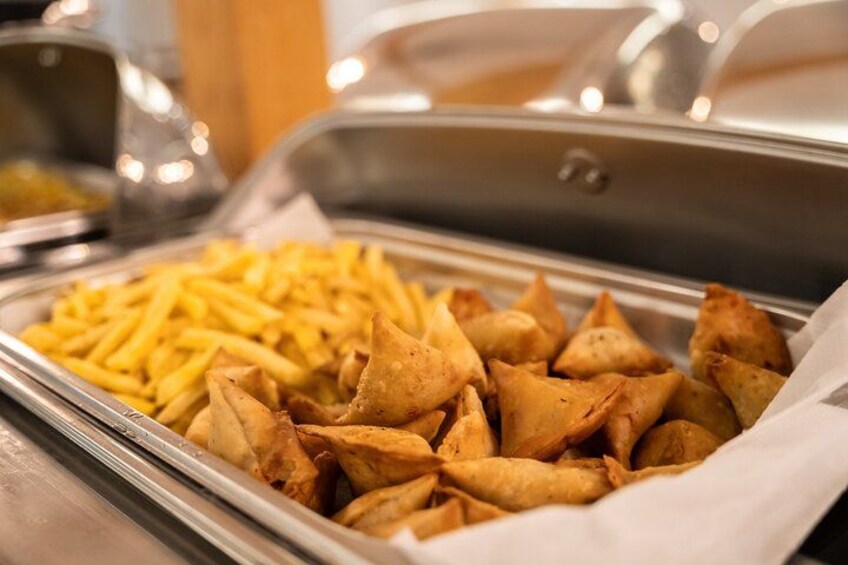 A buffet with French fries and samosas. 3