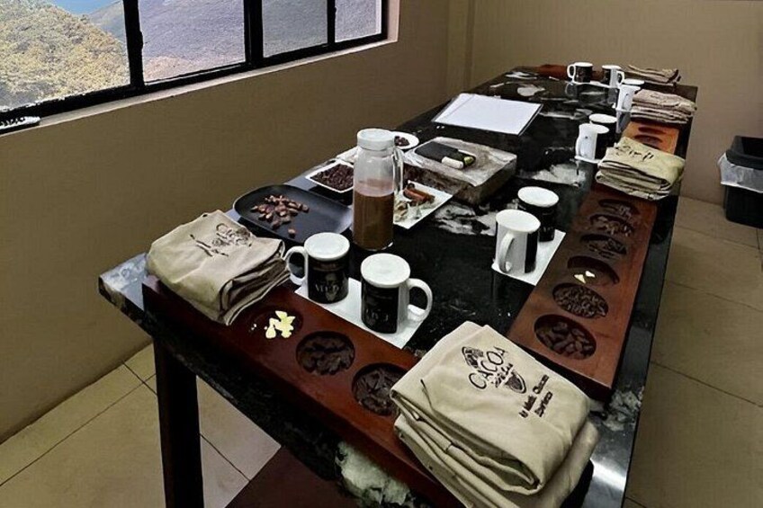 A coffee tasting setup with coffee beans, mugs, and a coffee grinder on a table. 4