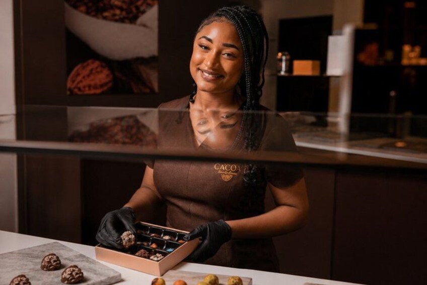 A person in a kitchen setting, wearing a brown apron, handling a box of cookies. 2
