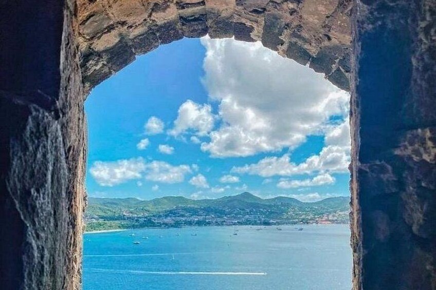 A stone archway framing a coastal view with mountains and a clear sky. 2