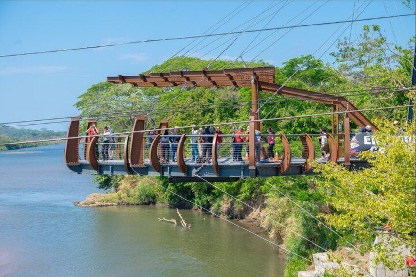 A pedestrian bridge over a river with people walking. 1