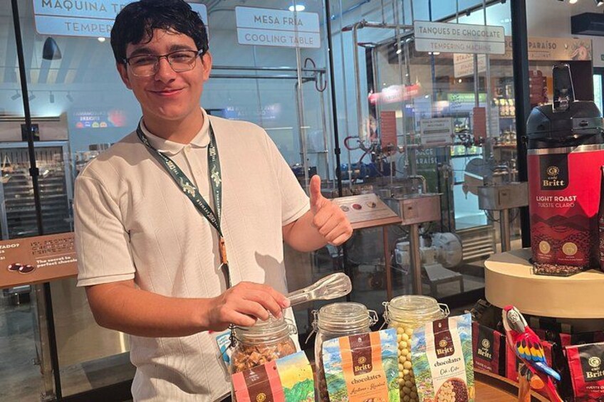 Une personne se tient devant un présentoir où sont exposés des pots de chocolat et une machine à café de la marque britannique spécialisée dans les cafés à torréfaction légère. 4