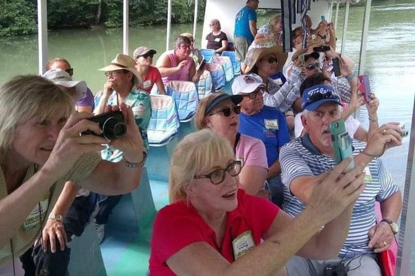 A group of people on a boat, some taking photos. 4