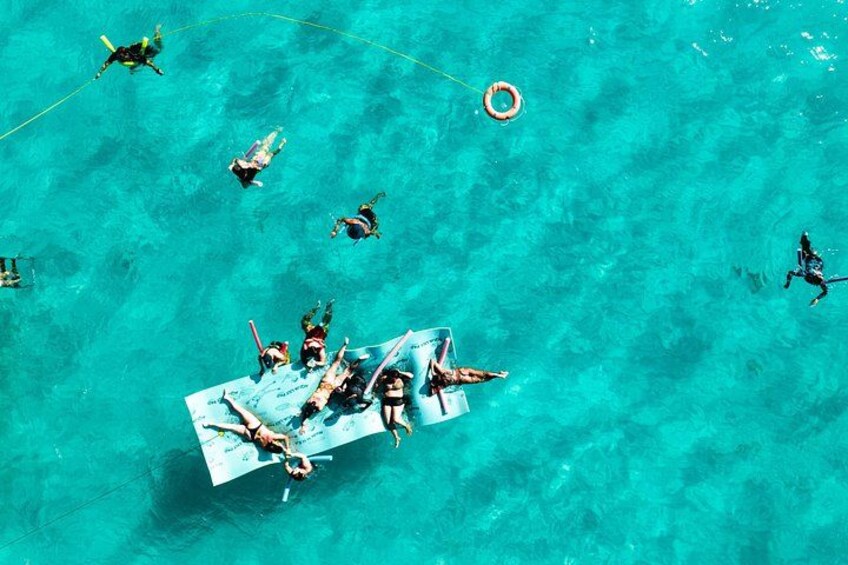 Un grupo de personas haciendo snorkel en aguas turquesas y transparentes. 2