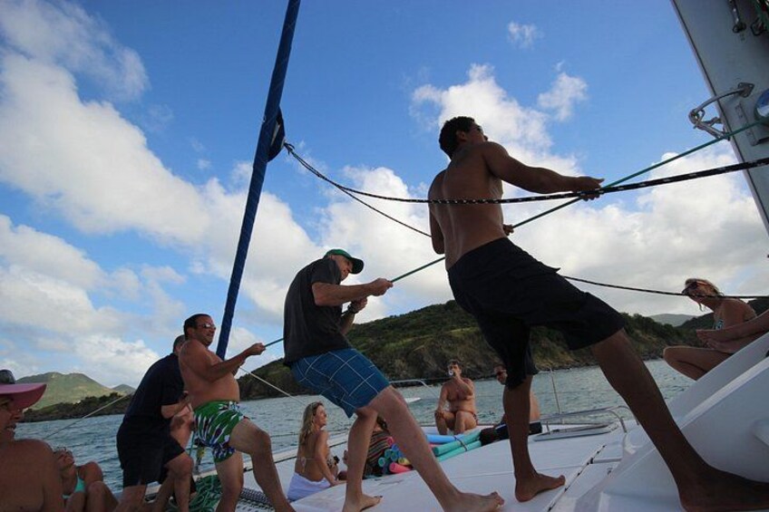 People on a boat, some standing and some sitting, with a rope between them. 2