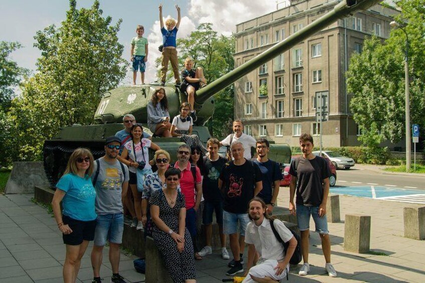 A group of people posing in front of a military tank. 3