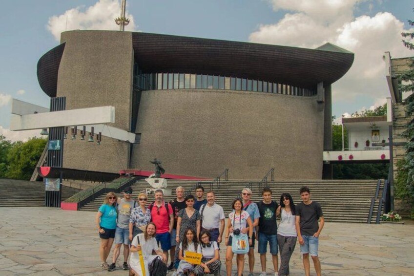 A group of people posing in front of a modern building with a unique architectural design. 4