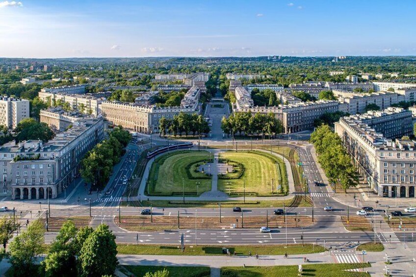 An aerial view of a city with a central square, surrounding buildings, and a distant landscape. 1