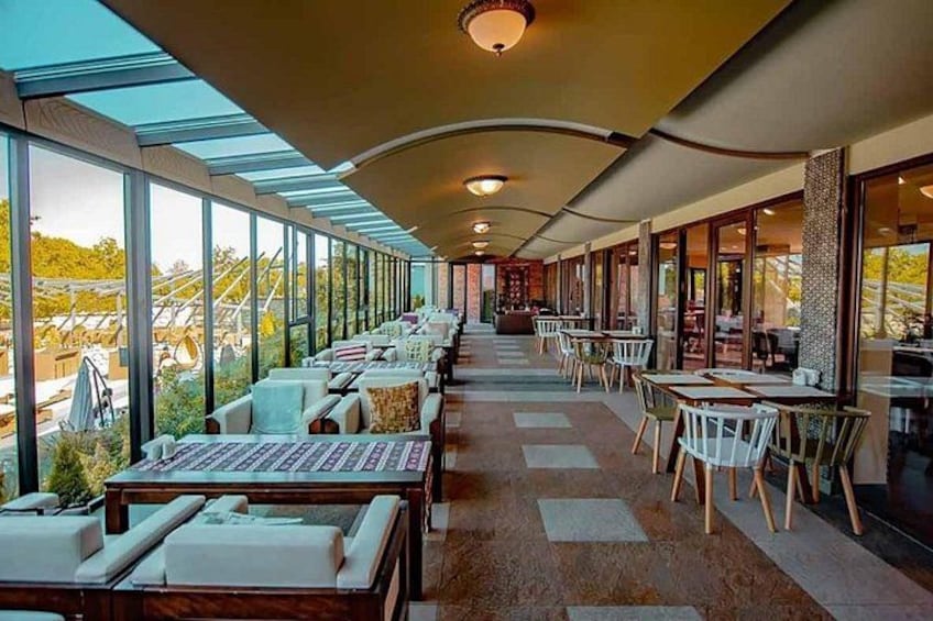 A modern indoor dining area with tables and chairs, large windows, and a view of the outdoors. 4