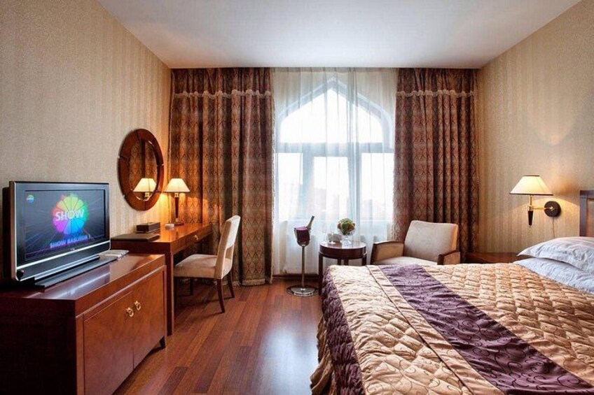 A hotel room with a bed, a desk, a television, and a window with curtains. 2