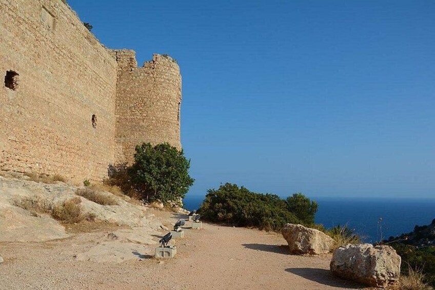 A coastal fortification with a clear view of the sea, a dirt path, and some vegetation. 2