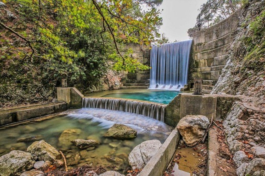 A waterfall cascading into a pool surrounded by rocks and greenery. 3