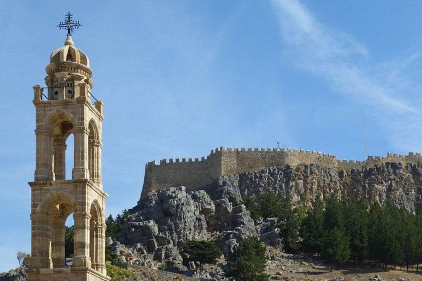 Una torre de campana de piedra y un castillo fortificado en una colina rocosa. 3