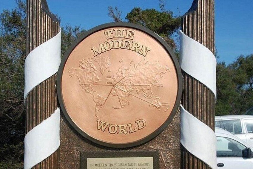 Een rond bord met een wereldkaart en de tekst 'THE MODERN WORLD' op een houten paal. 3