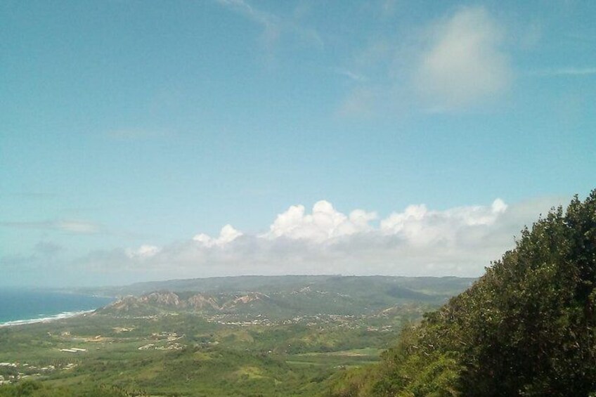A coastal landscape with a mountain range in the distance, a clear sky, and a view of the ocean. 3