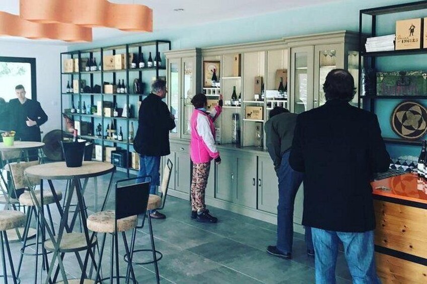 A wine tasting event with people standing around a display of wine bottles. 3