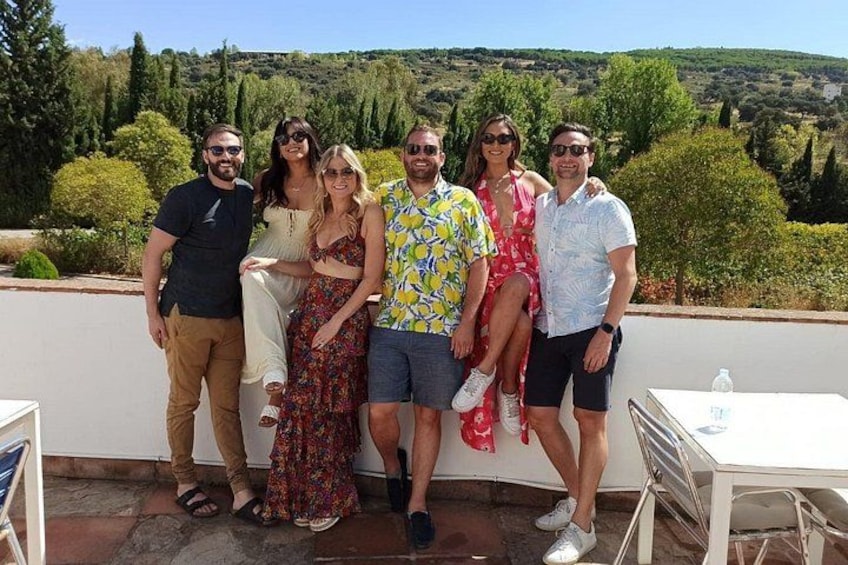 Un gruppo di persone in piedi su una terrazza con un panorama mozzafiato sullo sfondo. 1