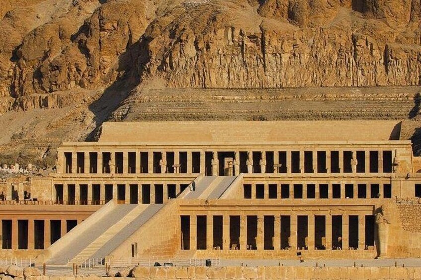 Un vaste temple de l’Égypte ancienne, doté d’une entrée à gradins et d’une grande statue en premier plan. 1