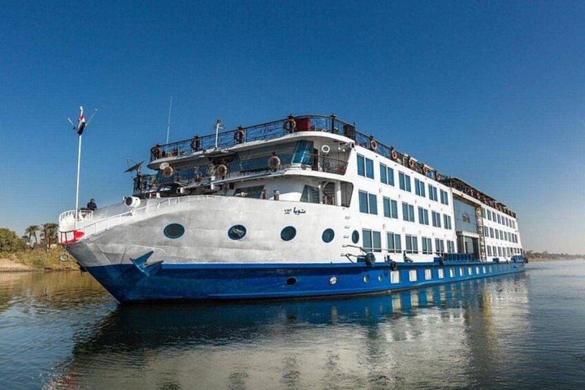 Un gran barco crucero fluvial de varias cubiertas con decoración blanca y azul, navegando sobre aguas tranquilas. 3