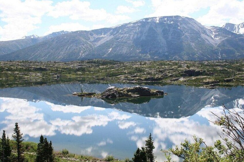 Un lac de montagne aux eaux miroitantes, entouré d’arbres et bordé par une chaîne de montagnes. 2