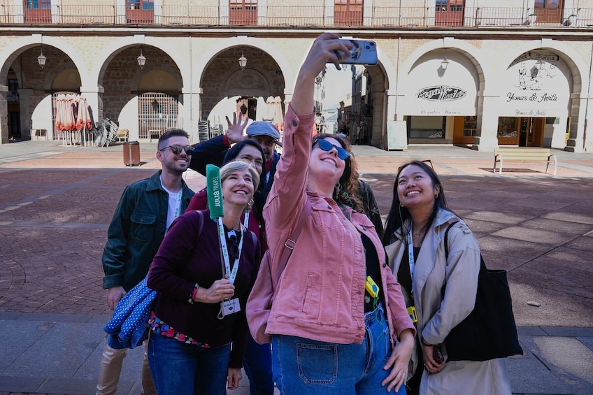 A group of people taking a selfie in a public square with historic buildings in the background. 1