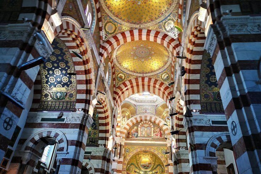 En katedralinteriör med randiga valv, utsmyckade tak och religiösa symboler. 2