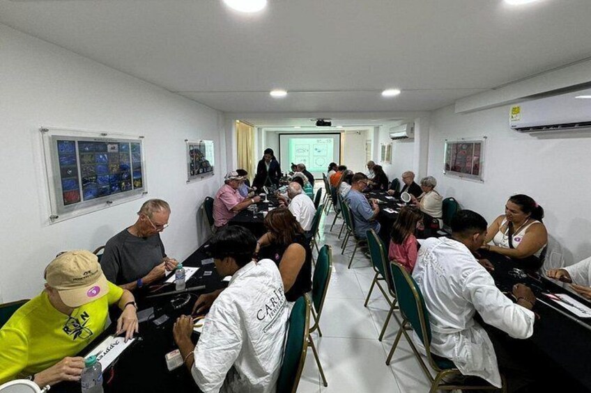 A conference room with people seated at tables, engaged in a meeting. 2