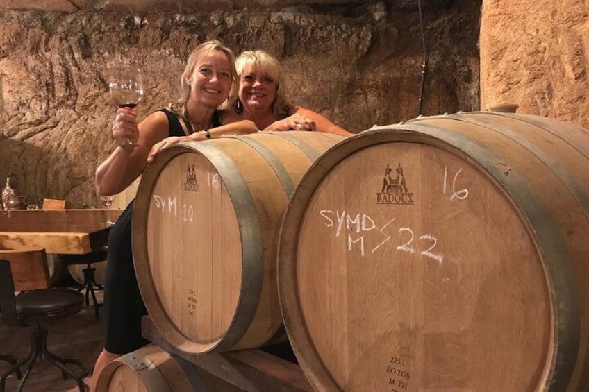 Deux personnes assises sur de grandes cuves en bois utilisées pour le vin, dans une cave. 1