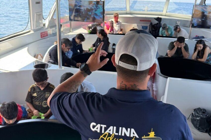A boat with people seated, a man in a blue shirt with 'CATALINA' on the back, and a woman in a white top. 4