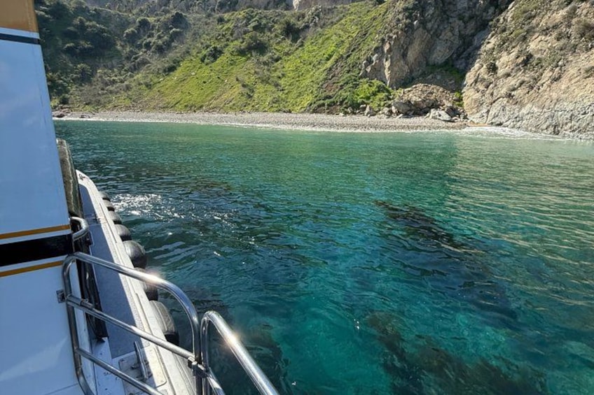 A boat on clear turquoise water with rocky cliffs in the background. 2