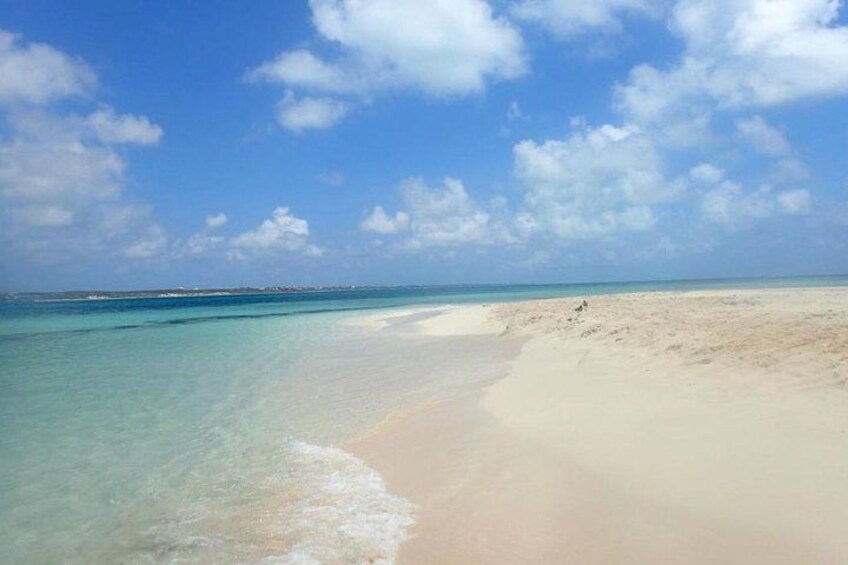 A beach with clear turquoise water, sandy shore, and a distant shoreline. 5