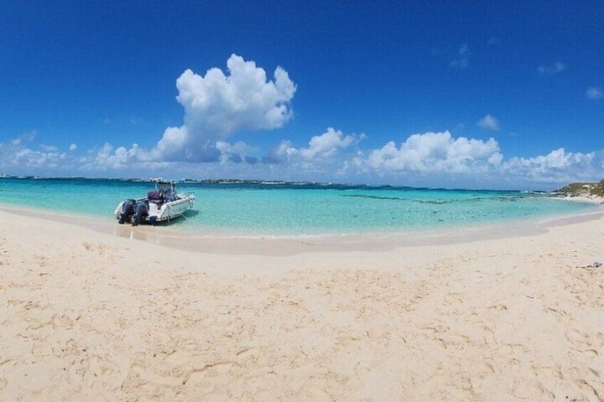 A beach with a boat on the shore and clear turquoise water. 2