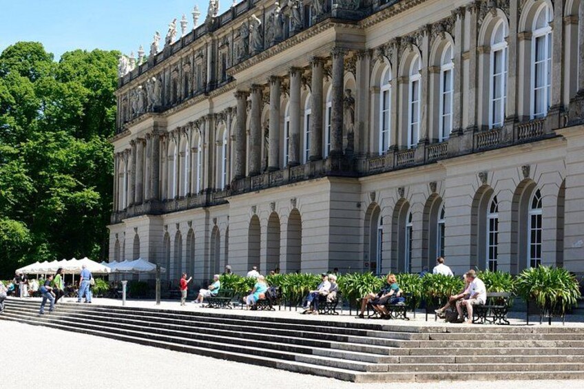 A historic building with classical architecture, a staircase, and people sitting on benches. 1