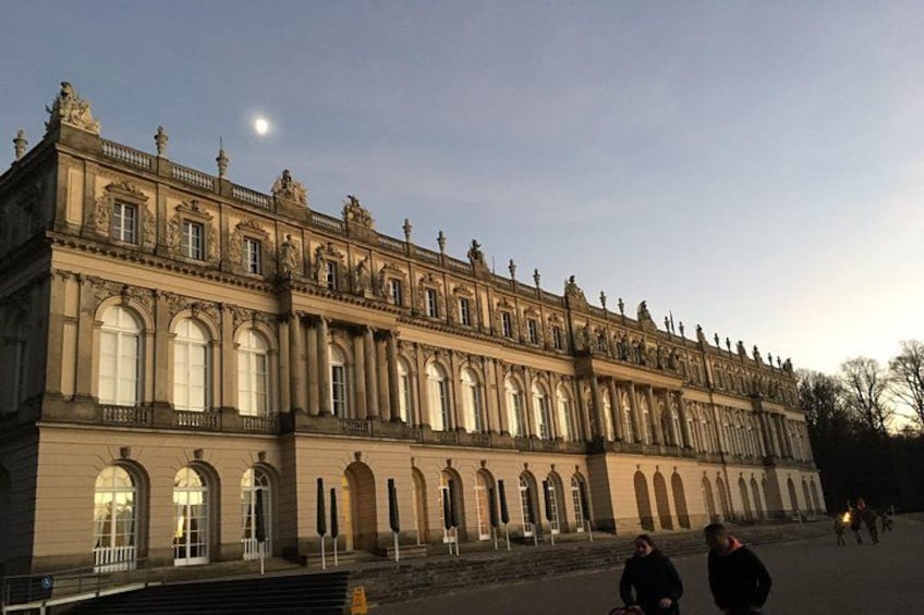 A large, historic building with arched windows and statues on the roof. 2