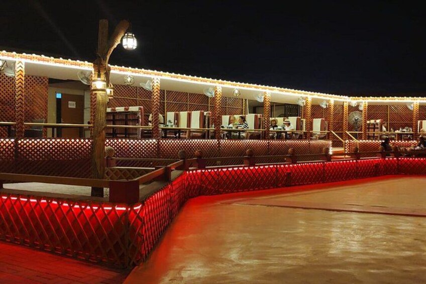 Un área de estar exterior bien iluminada con luces rojas y un cerco de madera. 4