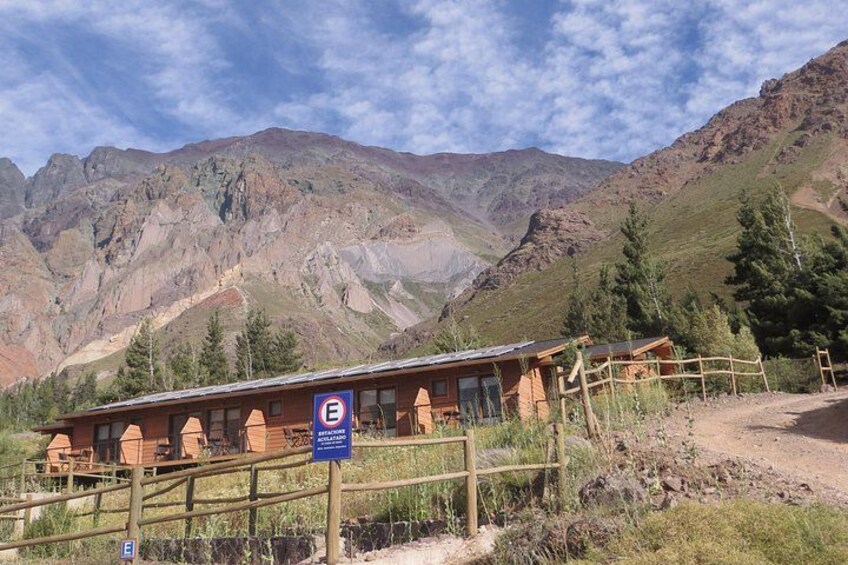 A mountain lodge with a wooden fence and a sign indicating a parking area. 2