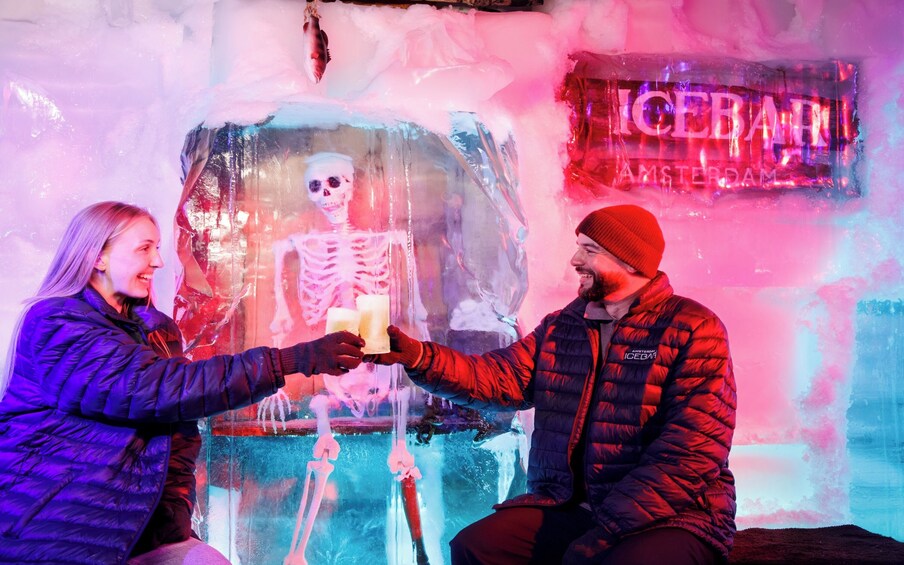 Deux personnes tenant des glaçons devant une grande sculpture de glace représentant un squelette. 5