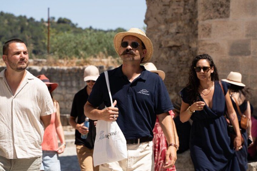 People walking near a historical stone wall, some wearing hats and sunglasses. 5