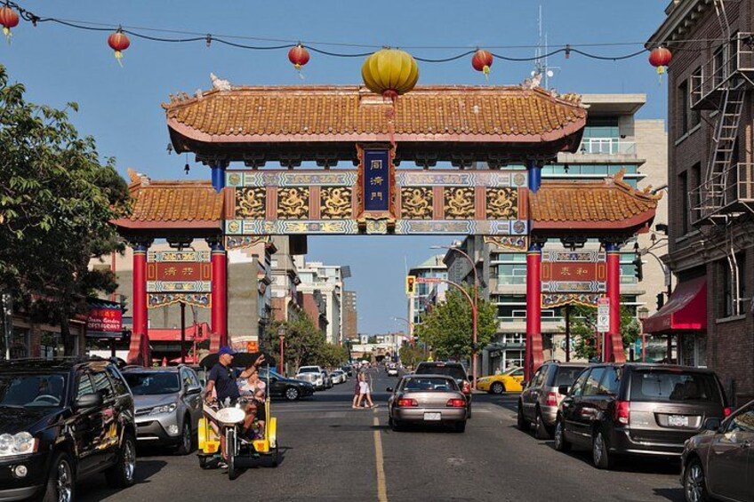 A street with a traditional Chinese gate, cars, and buildings. 2