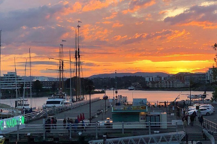 A waterfront with boats, a pier, and buildings in the background during sunset. 2