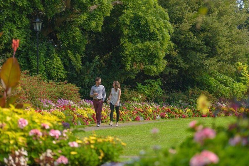 A couple walking on a path surrounded by colorful flowers and lush greenery. 4