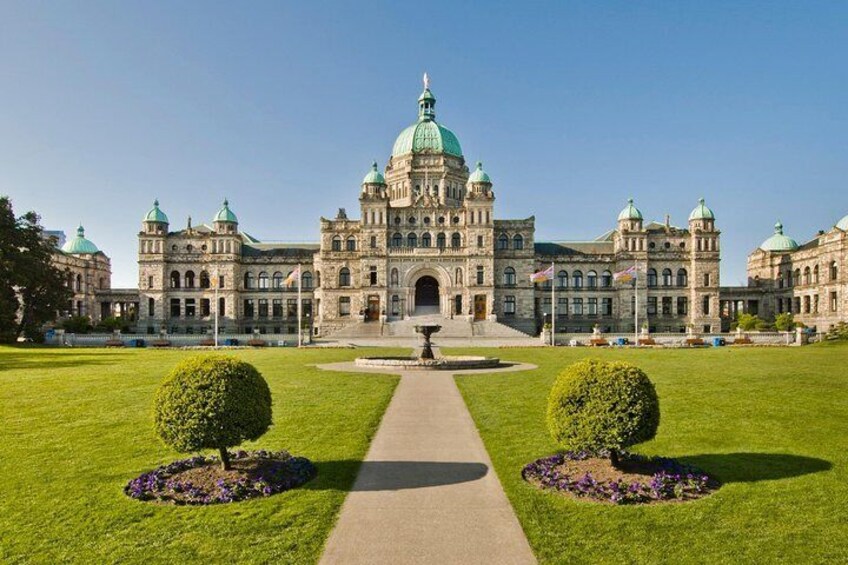 A large historic building with a central dome, surrounded by well-maintained lawns and flower beds. 3