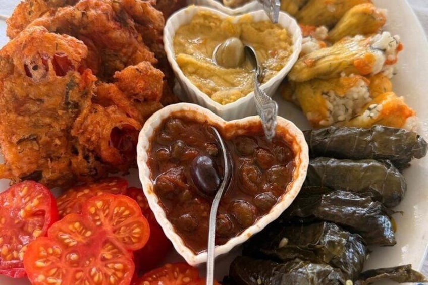 Un piatto di foglie di vite ripiene, una ciotola di salsa di pomodoro e diversi altri piatti. 2