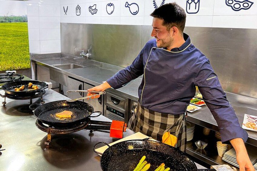 Un chef cocina en una cocina profesional con varias sartenes en la estufa. 2