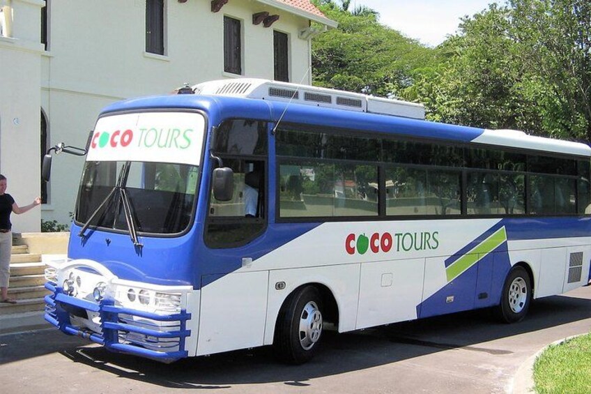 A blue and white bus with 'Coco Tours' branding parked in front of a building. 5